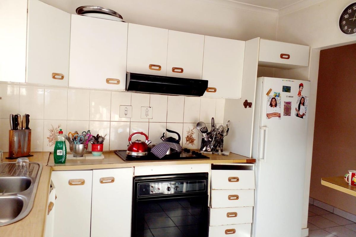 A functional kitchen featuring white cabinetry, laminate countertops, a built-in oven with hob, and a tiled backsplash, offering potential for modern updates.
