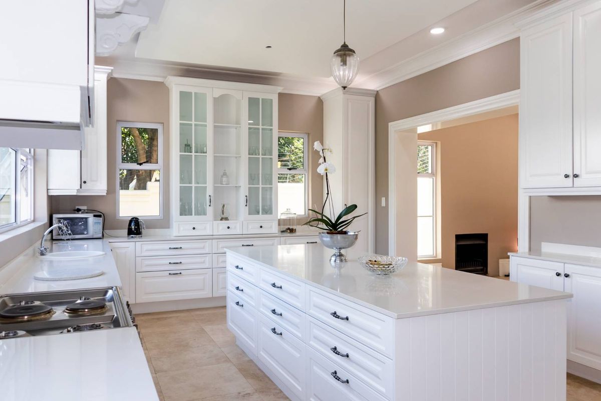 A bright, modern kitchen featuring white cabinetry, a large central island with quartz countertops, and high-quality finishes throughout.