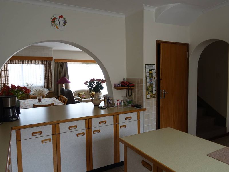 Open plan kitchen area featuring laminate countertops and built-in cabinetry, with an arched opening leading to the adjacent living and dining space.