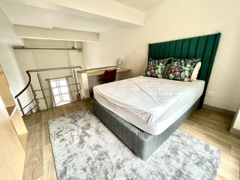 A loft-style bedroom featuring laminate flooring, a built-in desk area, and a mezzanine level with a metal safety balustrade.