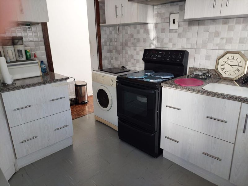 Functional kitchen featuring light wood-grain cabinetry, granite countertops, tiled backsplash, and a freestanding stove with an integrated laundry appliance.