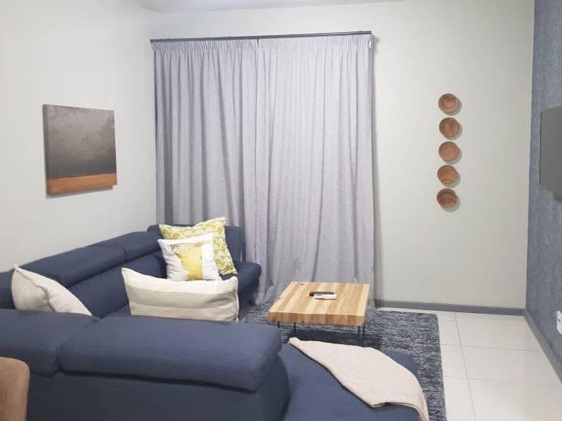 A comfortable living room featuring tiled flooring and a textured feature wall, providing a modern and inviting space for relaxation.