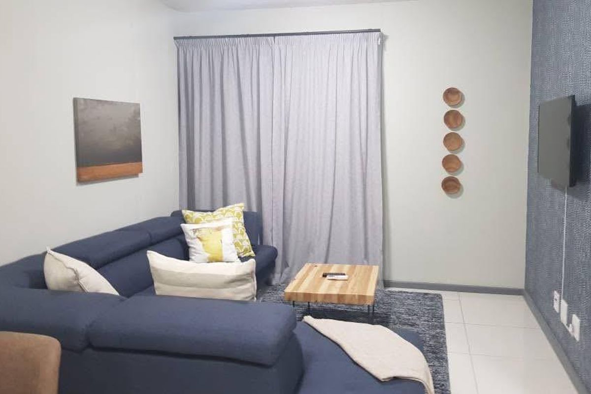 A comfortable living room featuring tiled flooring and a textured feature wall, providing a modern and inviting space for relaxation.