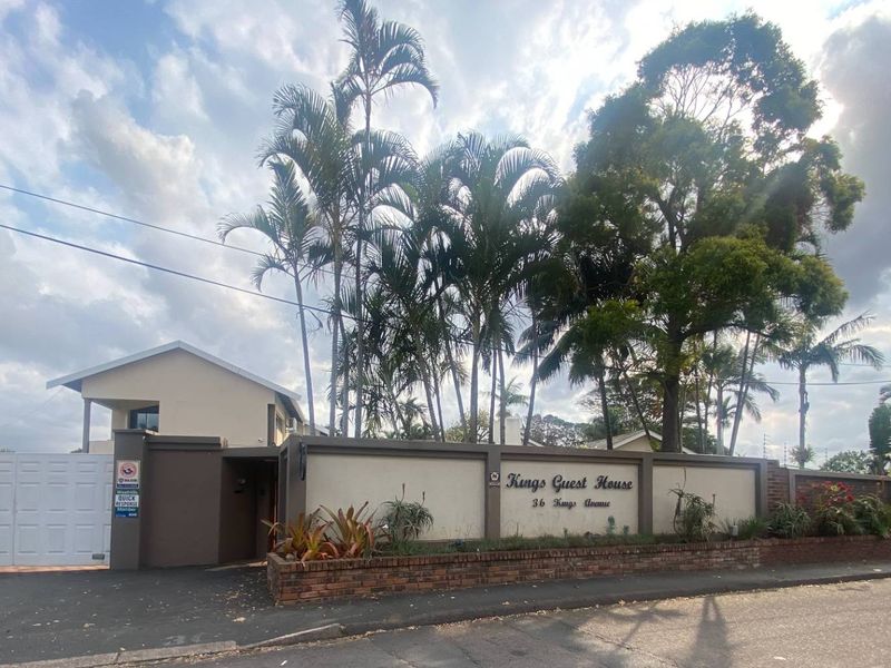 Front exterior view of the property featuring a secure boundary wall, gated entrance, and established garden landscaping.