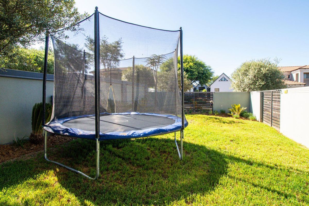 A private rear garden featuring a well-maintained lawn, perimeter boundary walls, and timber fencing.
