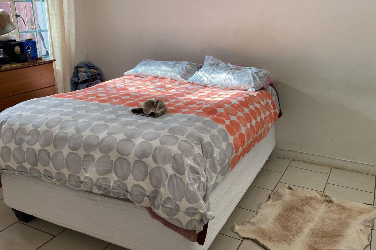 A functional bedroom featuring tiled flooring and natural light from a side window.