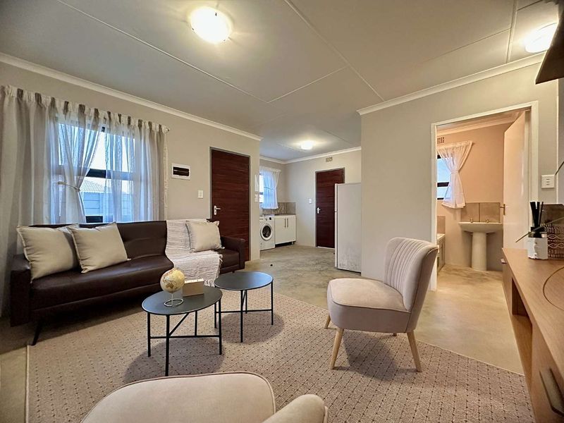Open plan living area featuring polished concrete floors, integrated kitchen cabinetry, and access to an adjoining bathroom with a pedestal basin.