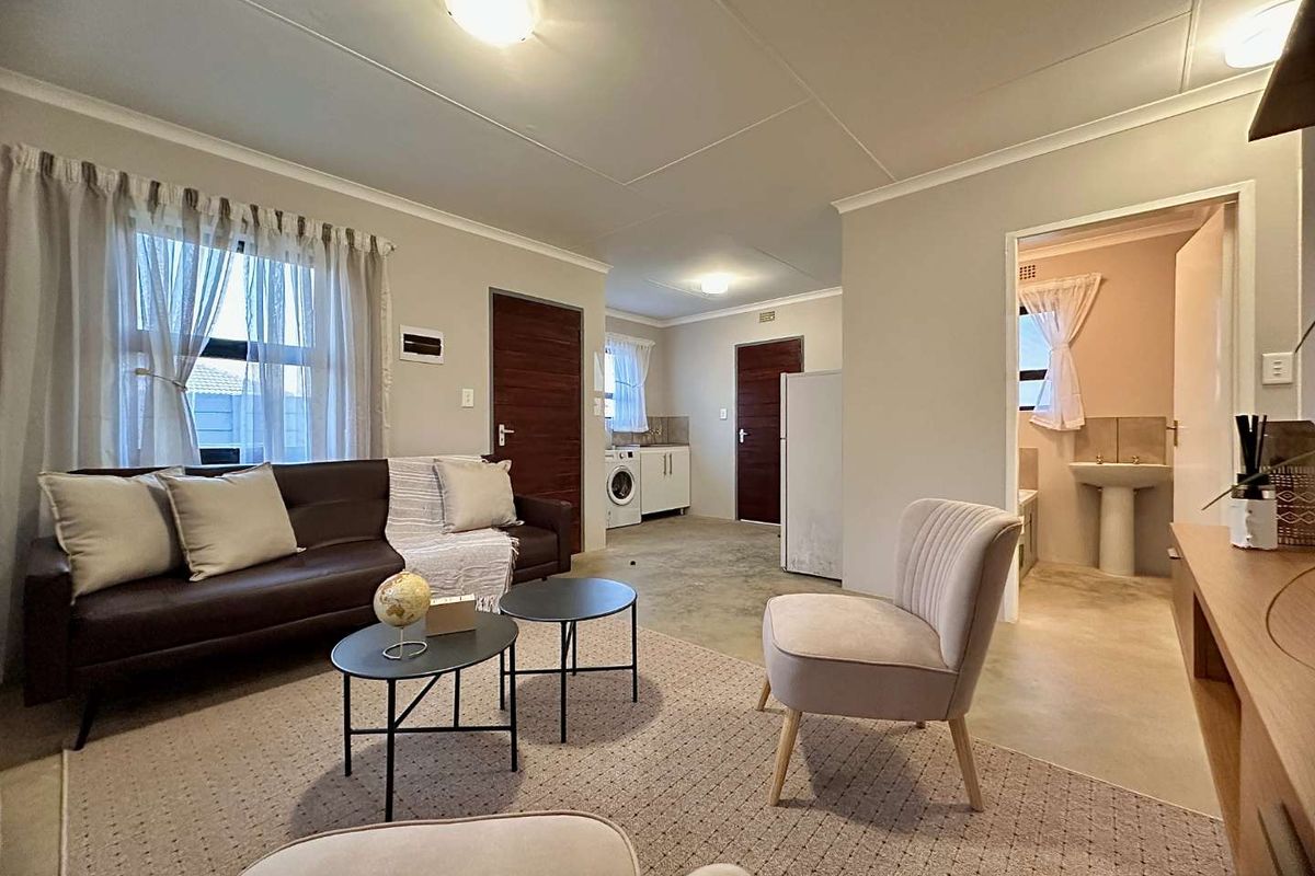 Open plan living area featuring polished concrete floors, integrated kitchen cabinetry, and access to an adjoining bathroom with a pedestal basin.