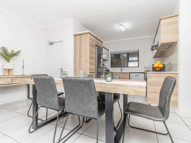 Modern open-plan kitchen and dining area featuring light wood cabinetry, tiled flooring, and a functional layout suitable for contemporary apartment living.