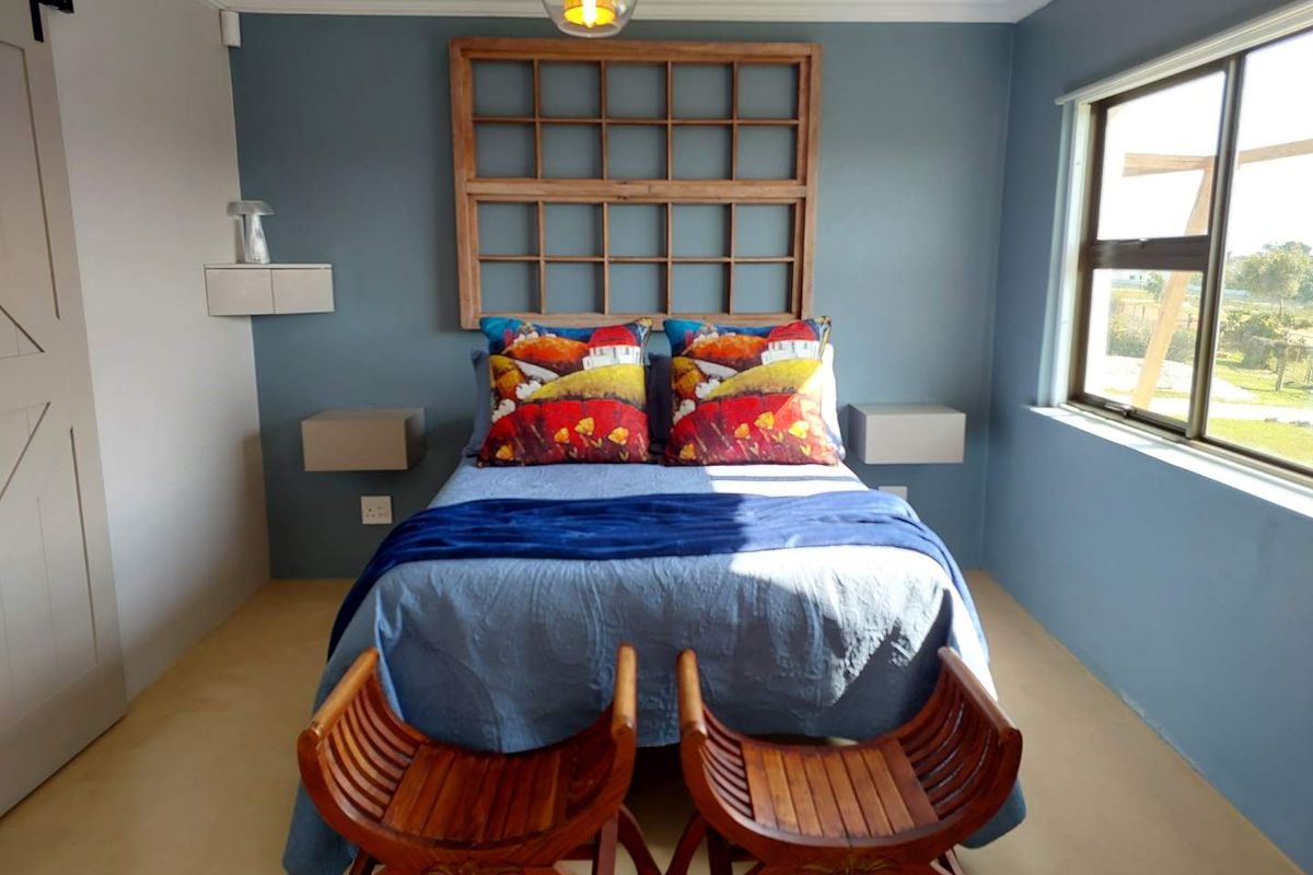 A well-maintained bedroom featuring polished concrete floors, a sliding barn door, floating bedside shelves, and crown molding with a modern blue accent wall.