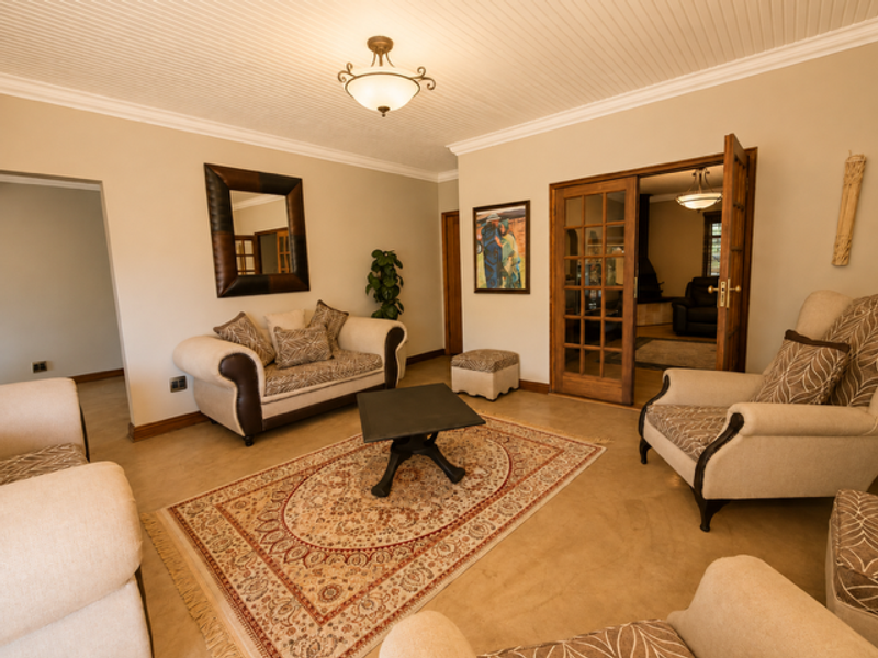 A well-maintained living room featuring polished concrete floors, beadboard ceiling detailing, crown molding, and elegant French doors leading to an adjacent space.