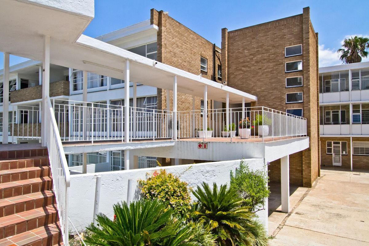 Exterior view of an apartment complex featuring brick facade, covered walkways, and metal balustrades with access stairs.