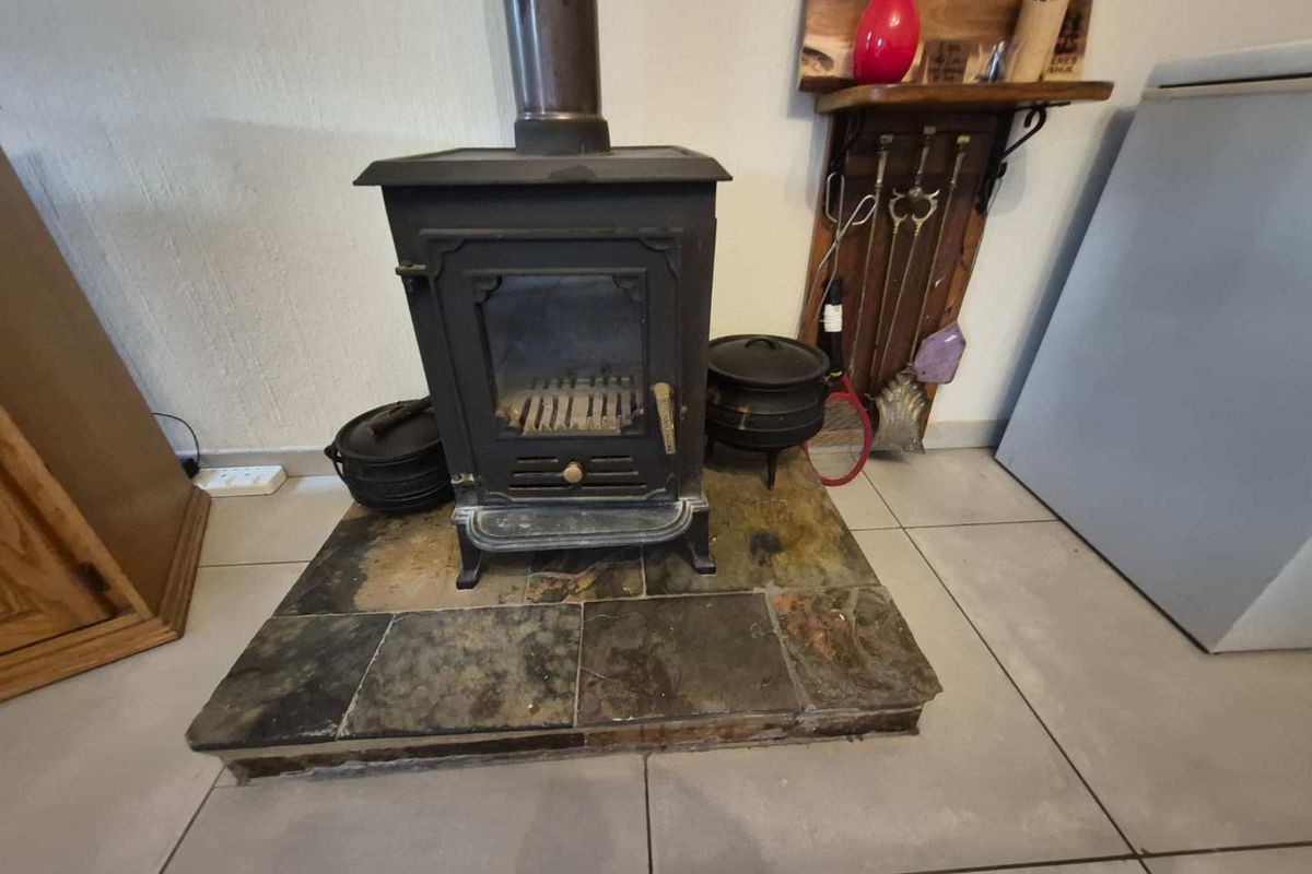 A living area featuring a cast iron fireplace set on a raised slate hearth with neutral tiled flooring.