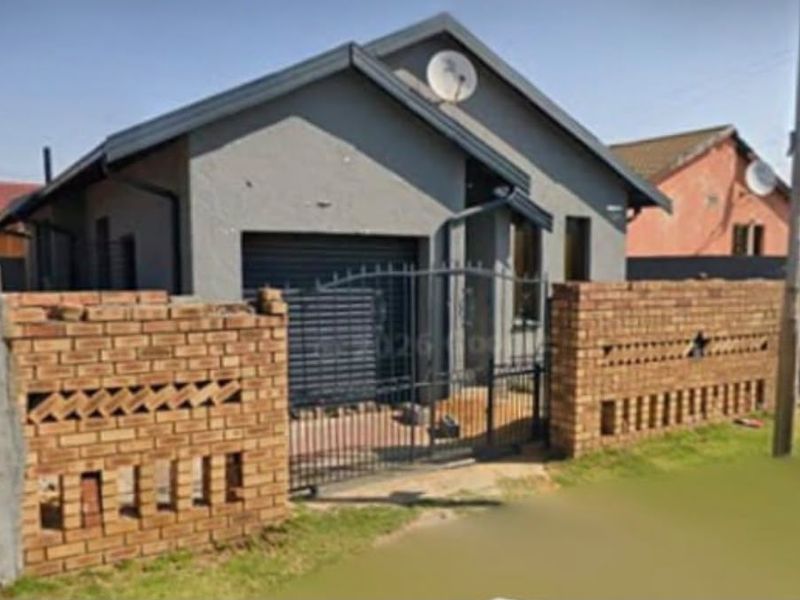 Front elevation of a single-story house featuring a brick boundary wall, metal security gate, and a roller shutter garage door.