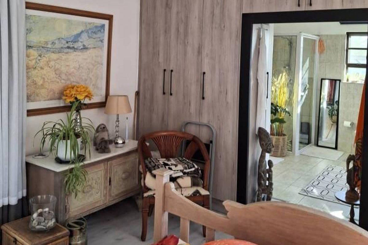 A bedroom featuring built-in wooden cupboards, an air conditioning unit, and direct access to an en-suite bathroom.