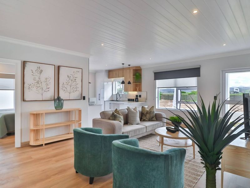 Modern open-plan living area featuring timber flooring, tongue and groove ceiling, and a sleek kitchen with contemporary cabinetry and finishes.