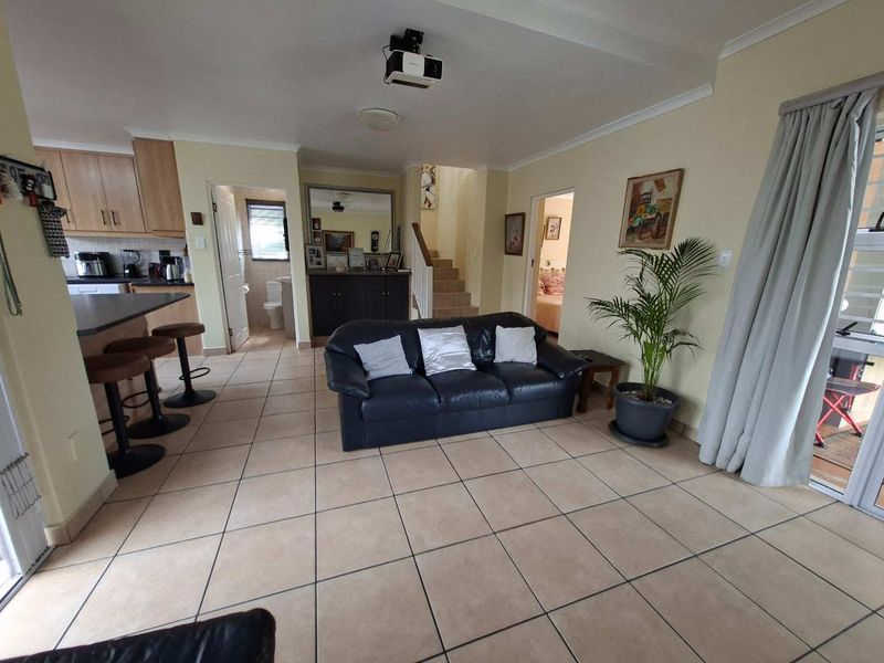 Open plan living area featuring tiled flooring, a kitchen with island, and a staircase leading to the upper level.