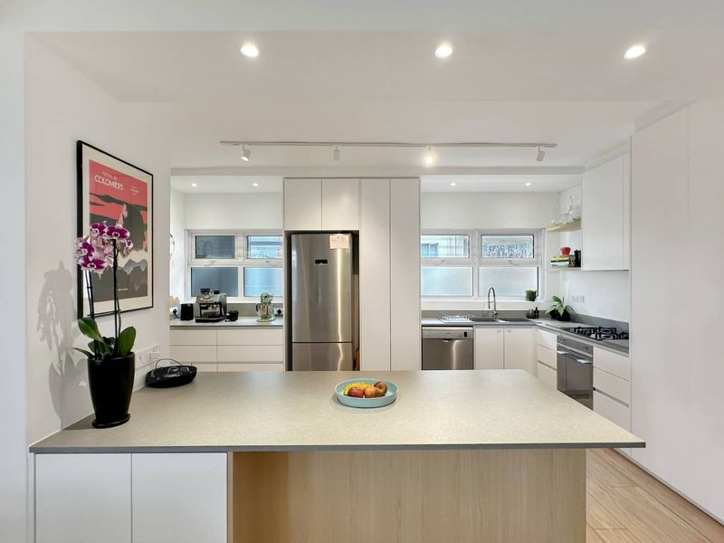 Modern, well-lit kitchen featuring clean white cabinetry, a functional island, stainless steel appliances, and contemporary recessed and track lighting.