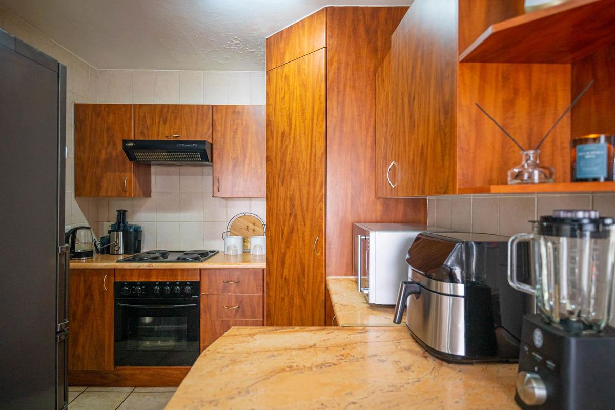 A functional kitchen featuring wood-finish cabinetry, stone-look countertops, a built-in oven, and an extractor fan.