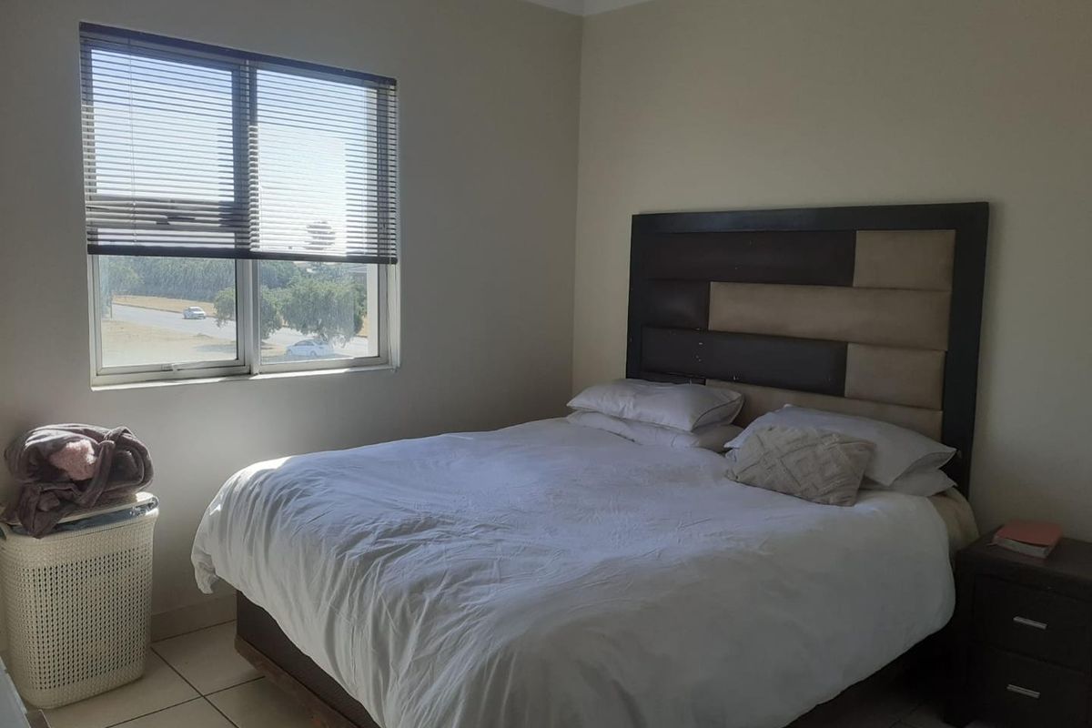 A bedroom featuring tiled flooring and a window fitted with venetian blinds, offering a functional and neutral living space.