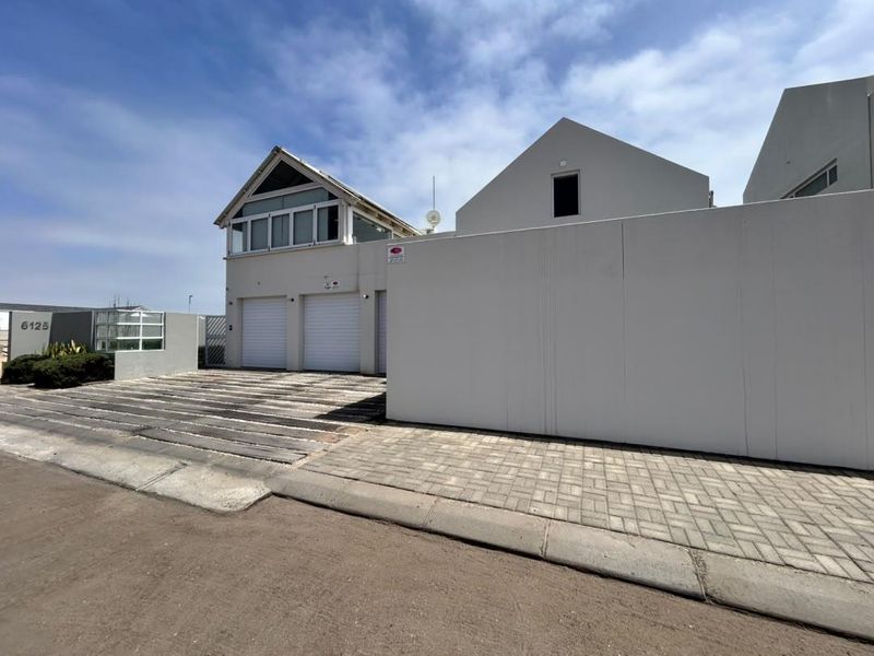 Front exterior view of a modern property featuring a triple garage, paved driveway, and clean architectural lines with a gabled roof design.