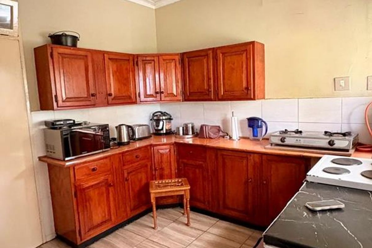 A functional kitchen featuring traditional wooden cabinetry, tiled flooring, and a basic layout with integrated counter space and built-in stove area.