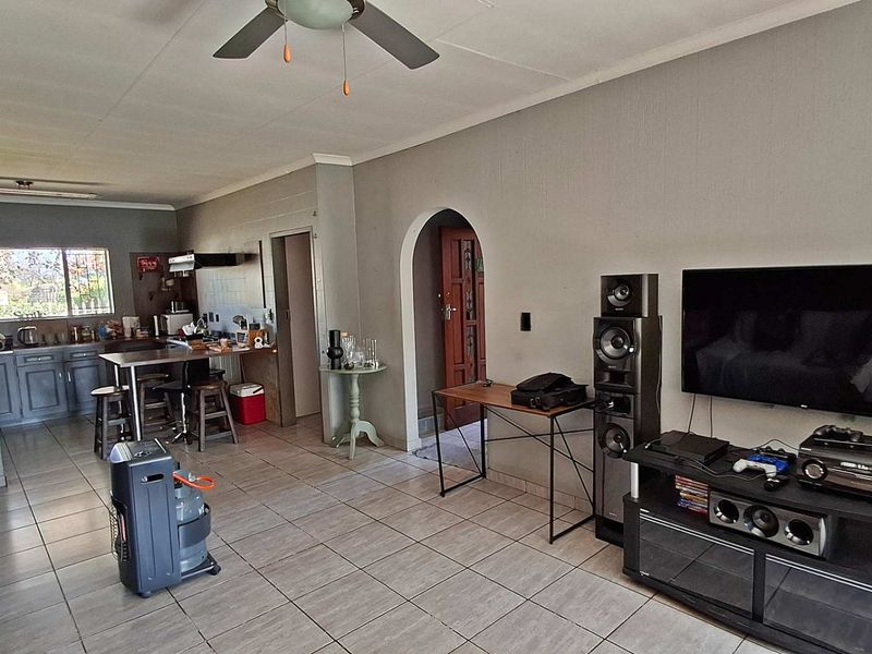 Open-plan living area featuring tiled flooring, a ceiling fan, and an integrated kitchen space with cabinetry and an archway entrance.