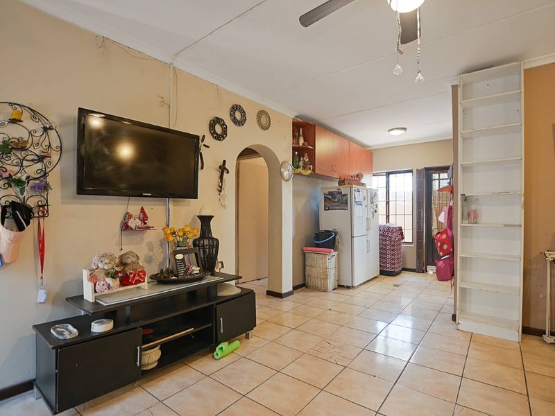 Open plan living area featuring tiled flooring, a ceiling fan, built-in shelving, and an arched transition leading to the kitchen area.