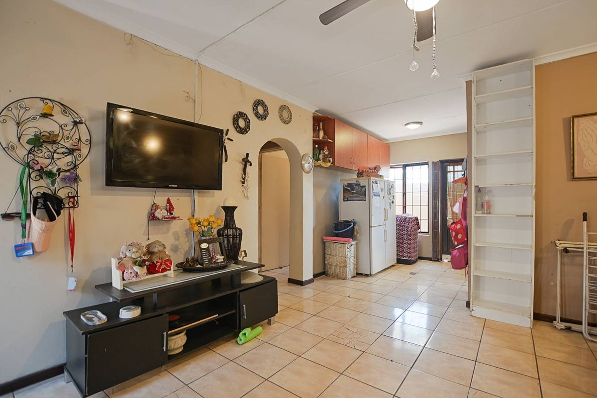 Open plan living area featuring tiled flooring, a ceiling fan, built-in shelving, and an arched transition leading to the kitchen area.