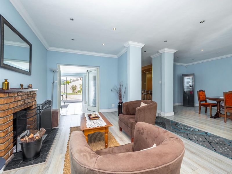 Open plan living and dining area featuring a brick fireplace, recessed lighting, crown molding, and direct access to the outdoor patio through glass doors.