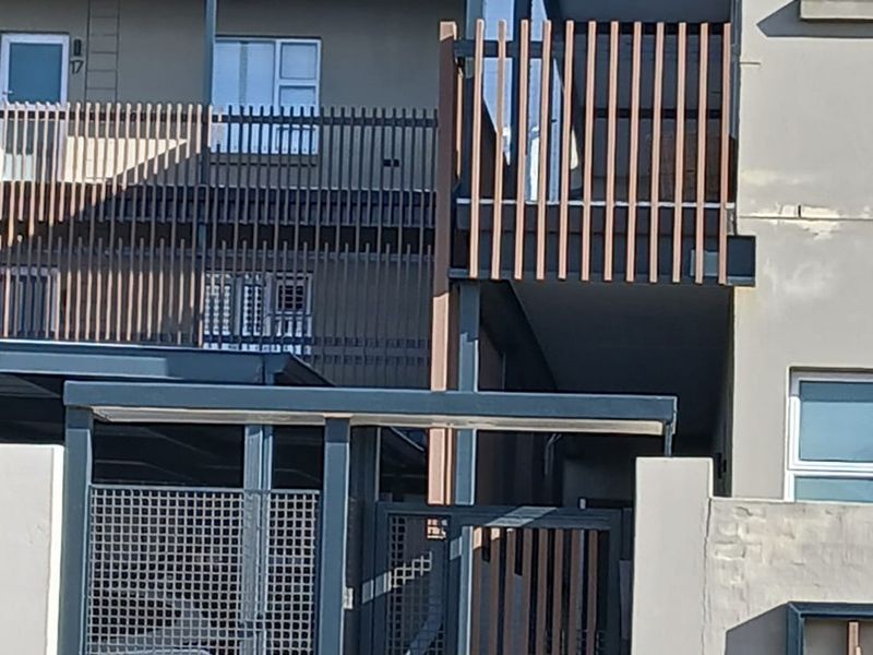 Front elevation of a modern apartment complex featuring timber slat balcony screens, metal security gates, and roof-mounted solar panels.