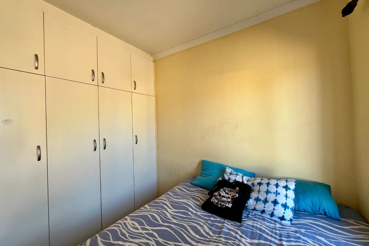 A bedroom featuring built-in floor-to-ceiling cabinetry with ample storage space and yellow painted walls.