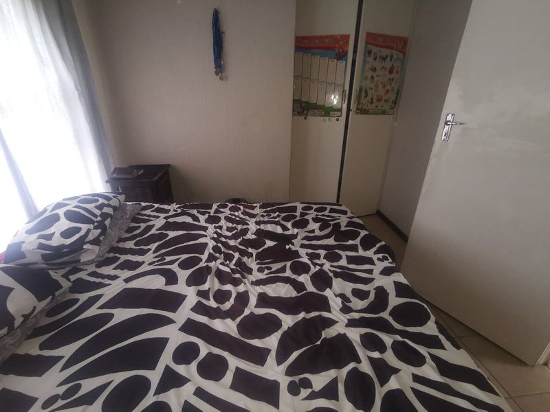A functional bedroom featuring built-in cupboards and tiled flooring, offering a practical layout for comfortable living.