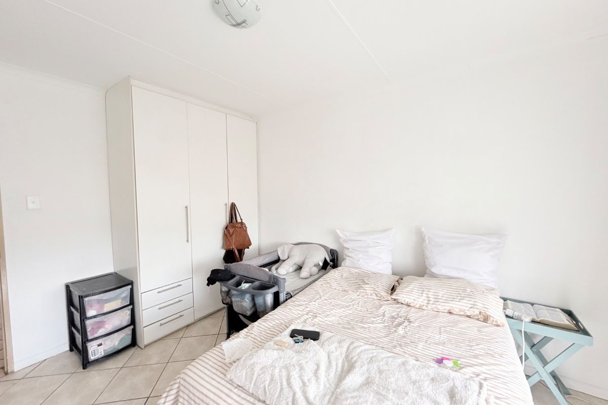 A functional bedroom featuring neutral tiled flooring and a built-in white wardrobe, offering a clean and simple space ready for personalization.