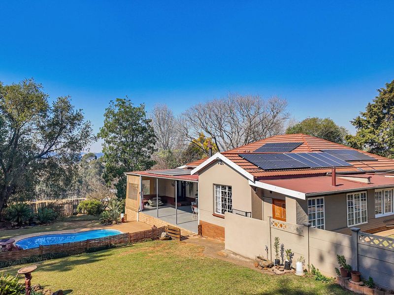 Rear view of the property featuring a swimming pool, covered patio, and solar panels installed on the tiled roof.