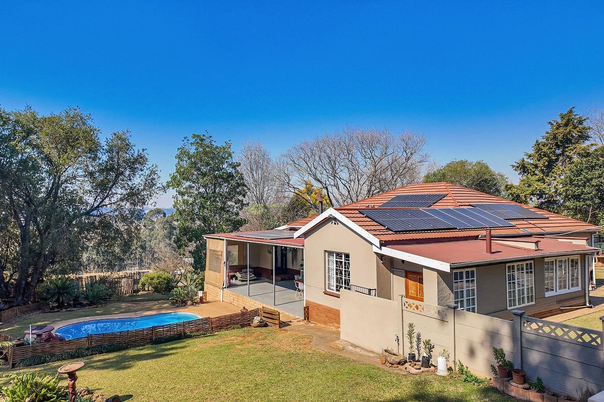 Rear view of the property featuring a swimming pool, covered patio, and solar panels installed on the tiled roof.
