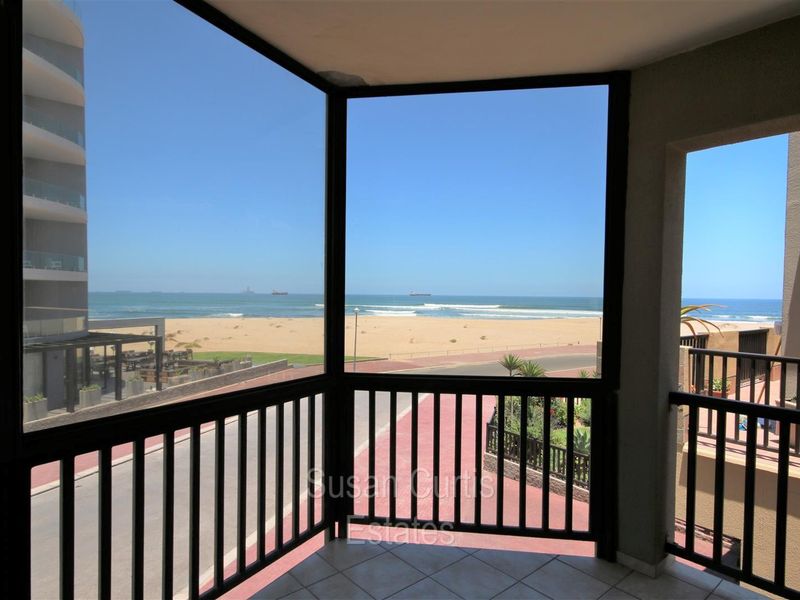 A covered balcony featuring tiled flooring and metal balustrades, offering direct, unobstructed views of the beach and ocean.