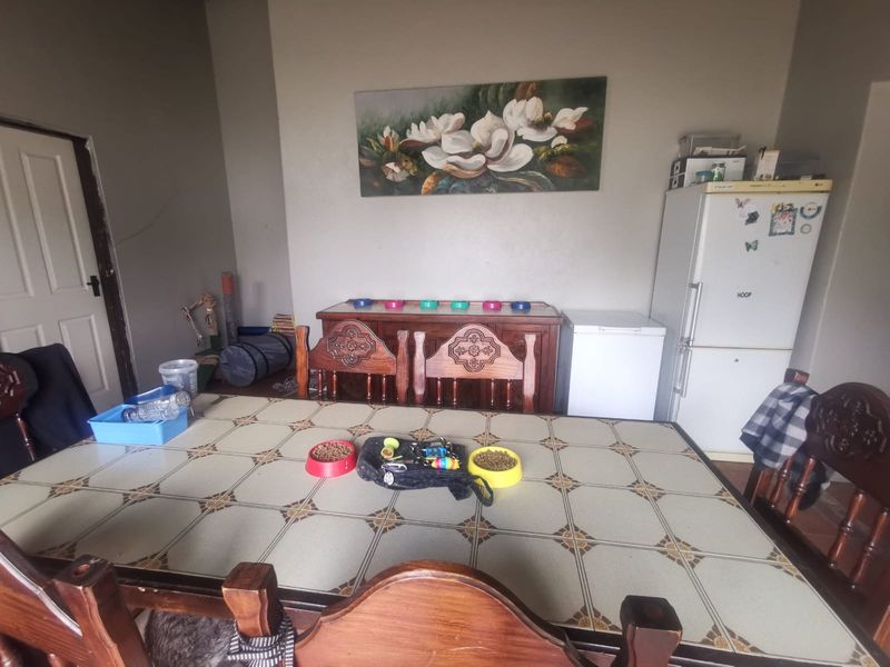 A dining area featuring a tiled table and visible wall cracks, requiring maintenance and cosmetic updates to improve the overall aesthetic.