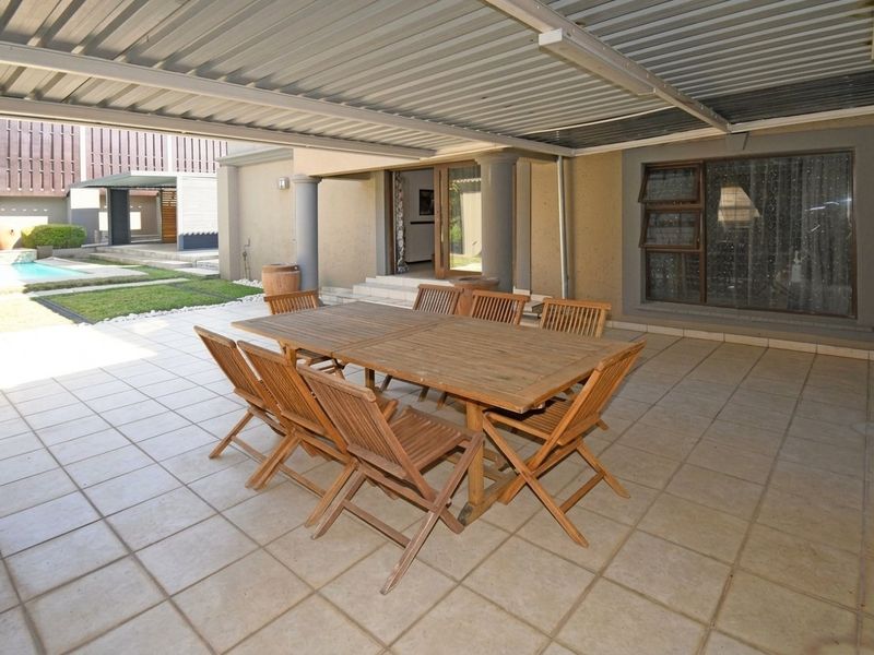 A covered outdoor patio area featuring tiled flooring, support columns, and direct access to the interior through sliding glass doors.