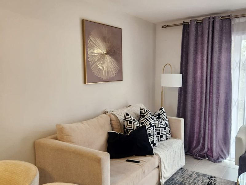 A cozy living room area featuring tiled flooring, a ceiling light fixture, and a sliding glass door leading to an outdoor space.