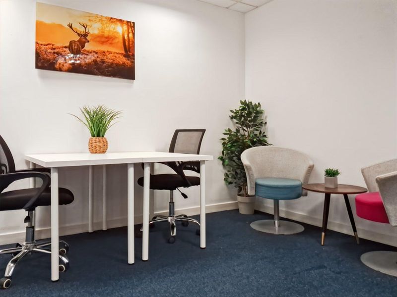 A functional office space featuring carpeted flooring and a suspended ceiling, suitable for a professional work environment.