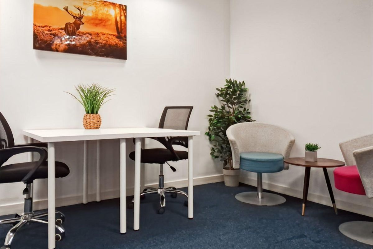 A functional office space featuring carpeted flooring and a suspended ceiling, suitable for a professional work environment.