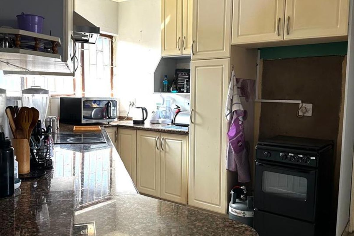 A functional kitchen featuring granite countertops, built-in cabinetry, and a dedicated space for a freestanding stove.