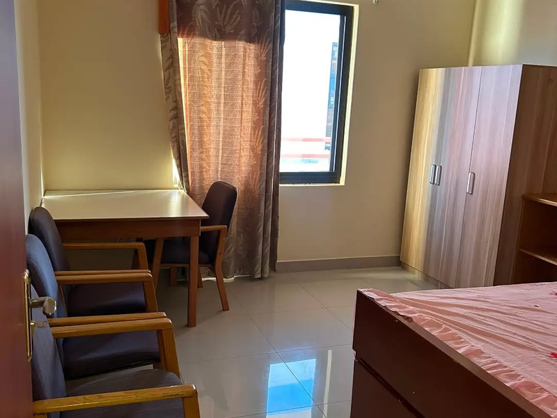 A bedroom featuring tiled flooring, a built-in wardrobe, and a window with curtains, providing a functional living space.