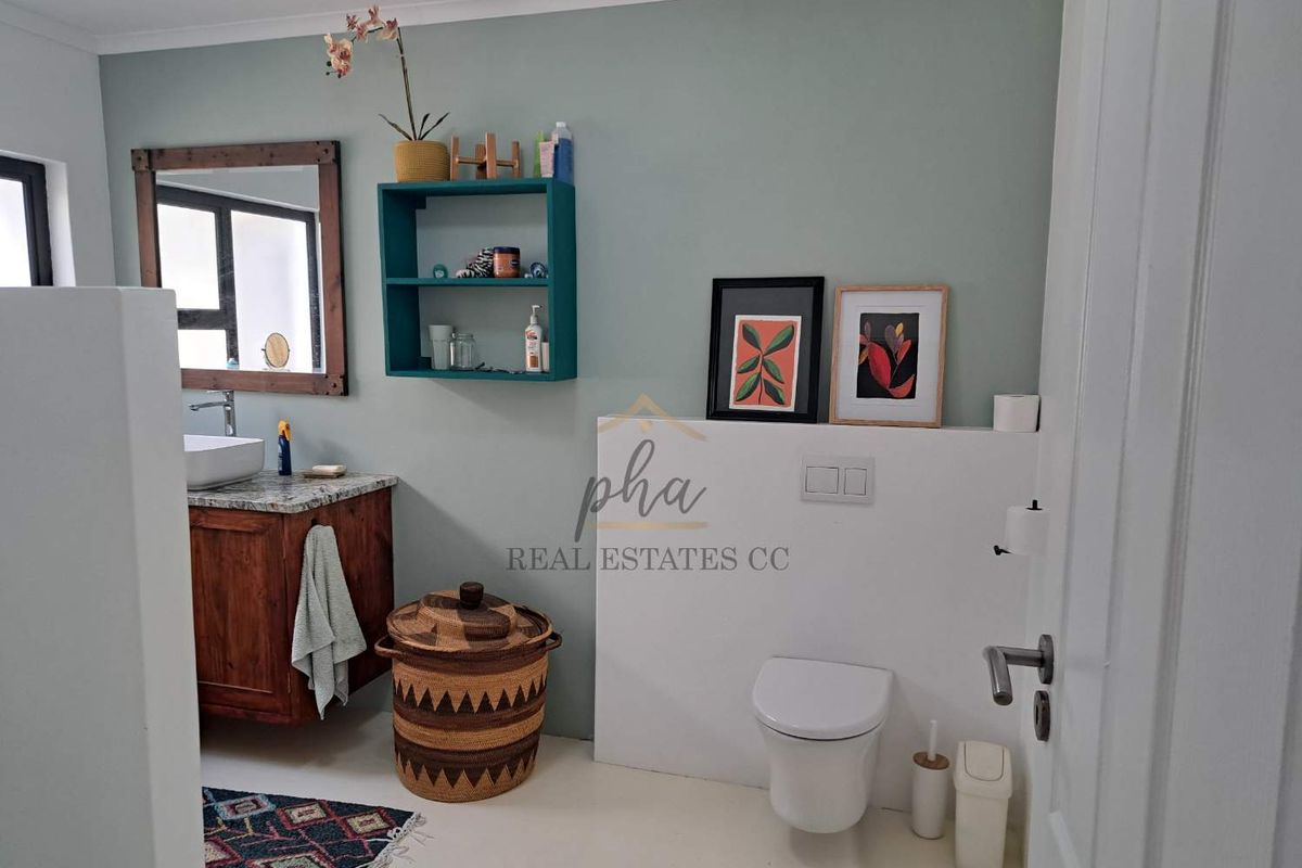 A modern bathroom featuring a wooden vanity with a vessel sink, wall-mounted toilet with a concealed cistern, and a framed mirror.