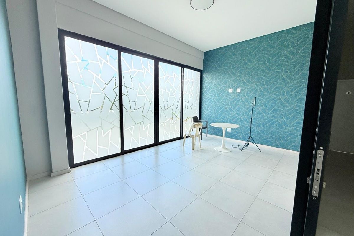 A bright living room featuring large sliding glass doors with decorative privacy film, tiled flooring, and a striking blue patterned accent wall.
