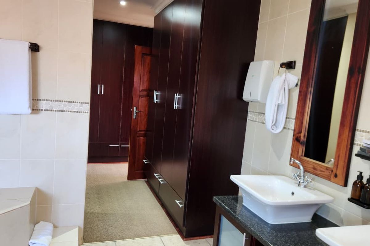 A well-appointed bathroom featuring dual vessel sinks on a granite vanity, tiled walls, and integrated dark wood cabinetry providing ample storage space.