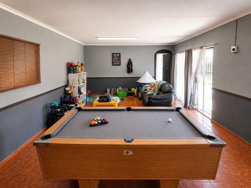 Spacious living area featuring tiled flooring, neutral grey walls with dado rail, and sliding glass doors providing access to the exterior.