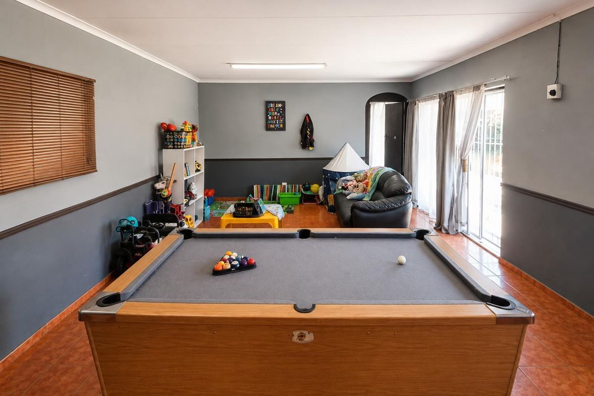 Spacious living area featuring tiled flooring, neutral grey walls with dado rail, and sliding glass doors providing access to the exterior.