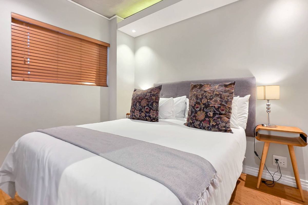 A well-maintained bedroom featuring hardwood flooring, recessed ceiling lighting, and timber venetian blinds, creating a clean and modern living space.
